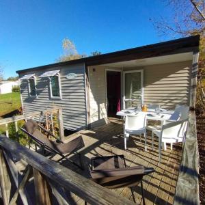 a small house with a deck with a table and chairs at Camping Lac aux Oiseaux - Mobil-home 3 Pièces 4 Personnes MAE-0991 in Martiel