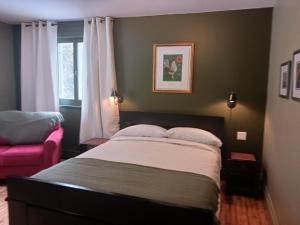 a bedroom with a bed and a pink chair at Auberge la maison sous les pins in Saint-Joseph-de-la-Rive