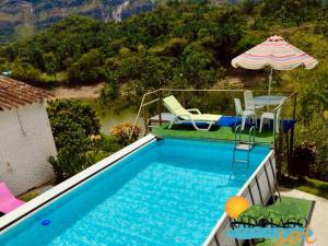 ein Pool mit Tisch, Stühlen und Sonnenschirm in der Unterkunft Pradolago Sol Prado Tolima in Prado