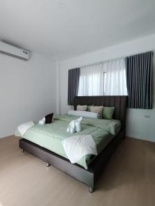 a bedroom with a large bed with green sheets at Harmony Villa in Wok Tum
