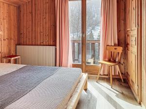 a bedroom with a bed and a chair and a window at Chalet Chalet chemin du four by Interhome in Morgins