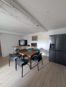 a dining room with a table and chairs and a refrigerator at Chambres des Gatinelles in Erbray