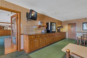 a kitchen with wooden cabinets and a tv on the wall at Garrison Inn and Suites in Garrison