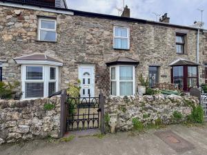 a stone house with a gate and a stone wall at 23 Beach Road in Y Felinheli