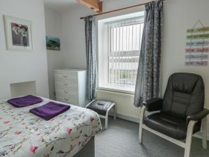 a bedroom with a bed and a chair and a window at 23 Beach Road in Y Felinheli