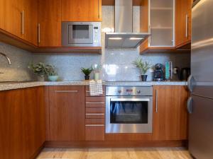 a kitchen with wooden cabinets and a stainless steel oven at Studio Justina by Interhome in L'Ampolla +17 photos