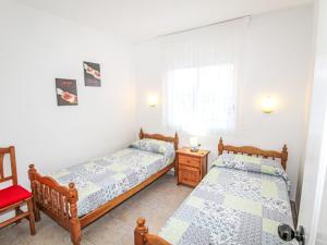 a twin bedroom with two beds and a chair at Apartment Sa Guilla by Interhome in Pals