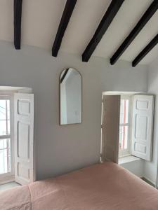 a bedroom with a bed and two windows and a mirror at Casa Cookie in Ojén
