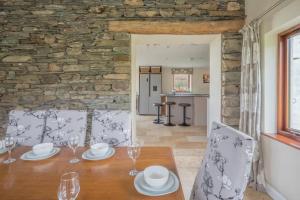 a dining room with a table and chairs and a stone wall at Spacious Barn Conversion 4 Bedroom Hot Tub - Pass the Keys in Seathwaite