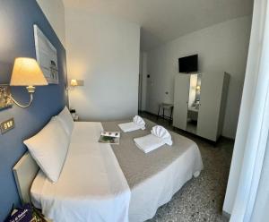 a bedroom with a large white bed with two pillows at Hotel Alfa - SPIAGGIA INCLUSA con Formula All Inclusive 7 notti in Rimini
