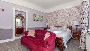 a bedroom with a bed and a red chair at Beaumont Windermere - Adults-Only Boutique Guest House- Free Parking & Wellness Access in Windermere