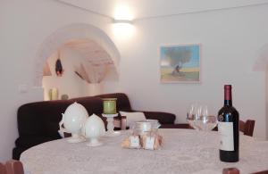 a table with a bottle of wine and glasses on it at BORGANTHIA in Alberobello
