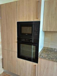 a black oven in a kitchen with wooden cabinets at Residence ocean view in Ngor +16 photos