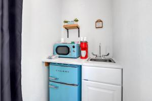 a small kitchen with a microwave and a blue refrigerator at The Container Retreat - 2B in Canyon Lake +3 photos