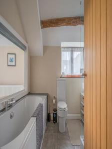 a bathroom with a white tub and a toilet at Spacious Barn Conversion 4 Bedroom Hot Tub - Pass the Keys in Seathwaite +76 photos