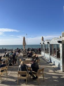 a group of people sitting at tables on the beach at Hôtel La Frégate in Fécamp