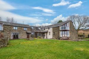 an exterior view of a stone house with a yard at Spacious Barn Conversion 4 Bedroom Hot Tub - Pass the Keys in Seathwaite