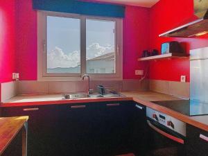 a kitchen with red walls and a sink and a window at Apartment U Centru by Interhome in Porto-Vecchio +17 photos