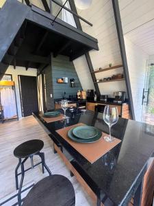 a kitchen with a table with plates and wine glasses at Cabana Encanto A-FRAME Com Cachoeira in Bocaina de Minas