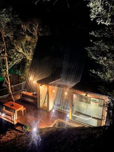 a small house with a wooden deck at night at Cabana Encanto A-FRAME Com Cachoeira in Bocaina de Minas