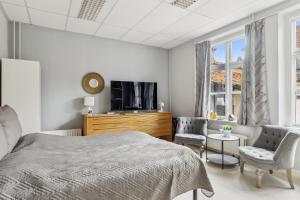 a bedroom with a bed and a tv and chairs at Det gamle Apotek Møn in Stege