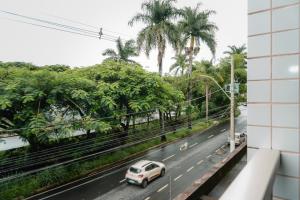a white car driving down a road with palm trees at Hotel Canaan in Sete Lagoas