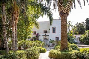 a palm tree in front of a white house at Masseria Buganvillea in Fasano