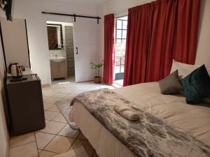 a bedroom with a large bed with red curtains at Feather Tree Bed and Breakfast in Centurion +75 photos