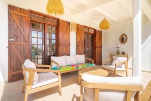 a living room with chairs and a couch and a table at Villa Bleue Papaye in Grand-Bourg