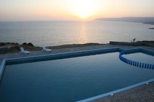 a swimming pool in front of the ocean at sunset at Terre d'Océan in Taghazout