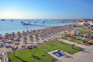 a beach with a bunch of umbrellas and the water at Pickalbatros White Beach Resort - Hurghada in Hurghada