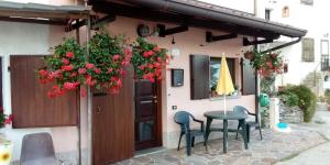 a table and chairs in front of a building with flowers at Casa vacanze Malinini in Savogna