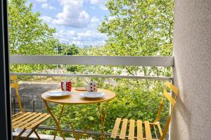 a table on a balcony with two cups and chairs at Relax-Parc des expos-Wifi by La clé des expos in Vanves