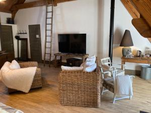 a living room with wicker chairs and a flat screen tv at Le Moulin de Visargent in Sens sur Seille