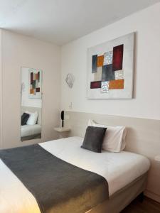 a bedroom with a large white bed and some paintings at Cit'Hôtel l'Europe - Cholet Gare in Cholet +47 photos