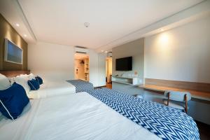 a bedroom with a large white bed and a television at Salinas Maragogi All Inclusive Resort in Maragogi