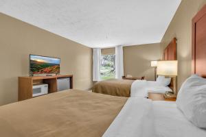 a hotel room with two beds and a flat screen tv at Bristol Arcadia Inn in Bristol
