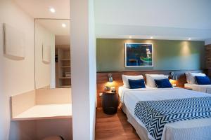 a bedroom with two beds and a mirror at Salinas Maragogi All Inclusive Resort in Maragogi