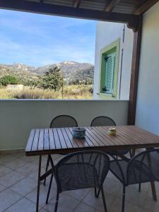 a wooden table and chairs on a balcony with a window at Naxos olive & home in Engares