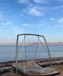 a swing on the shore of a body of water at Heaven Dune Camp in Nuweiba
