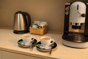 two cups of coffee on a counter next to a coffee maker at B&B La Littorina - Parcheggio Privato in Foligno