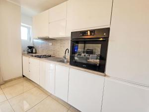 a kitchen with white cabinets and a black oven at Apartment Paz by Interhome in Donji Proložac