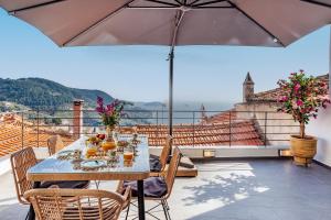 a table and chairs on a balcony with an umbrella at Larimis House in Loutraki