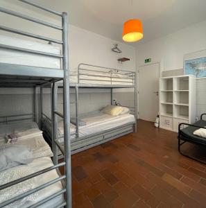 a room with three bunk beds and a lamp at Native Surfhouse in Praia da Areia Branca