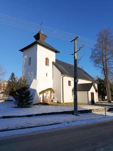 a white church with a steeple on the side of a street at Apartmán Forst in Nová Lesná