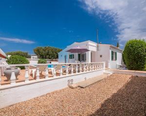 a white house with a fence and an umbrella at Villa Brehat avec piscine privée in Cala en Porter