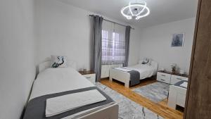 a white bedroom with two beds and a window at Sarajevo Central View Apartment in Sarajevo