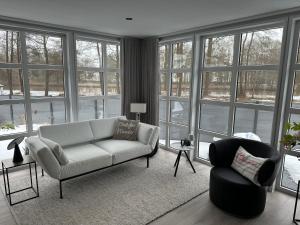 a living room with a couch and a chair and windows at Chalet Emsblick in Walchum +14 photos