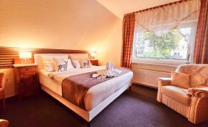 a bedroom with a bed and a chair and a window at Hotel Elisabeth Ilse in Braunlage