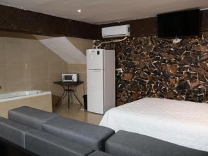 a bedroom with a white bed and a stone wall at Hotel Casa Patrón Parras in Parras de la Fuente